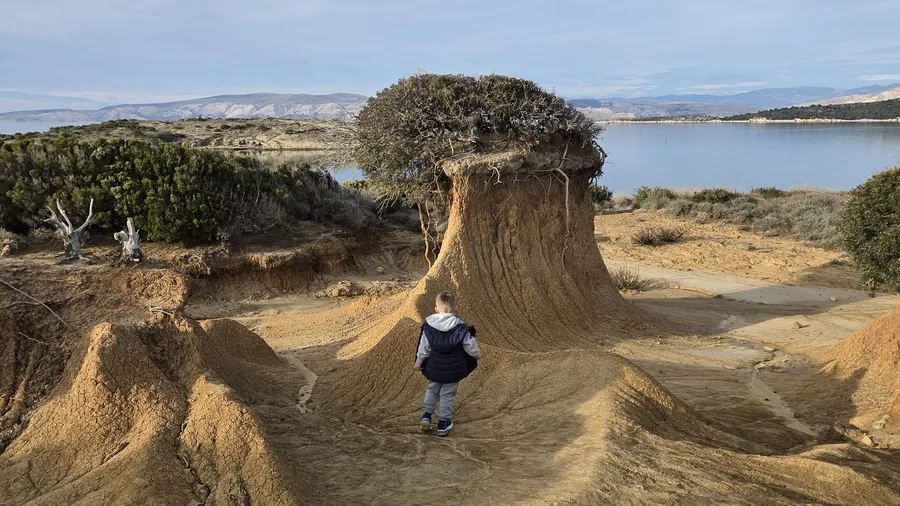 Child by the mushroom rock, natural landmark of Lopar