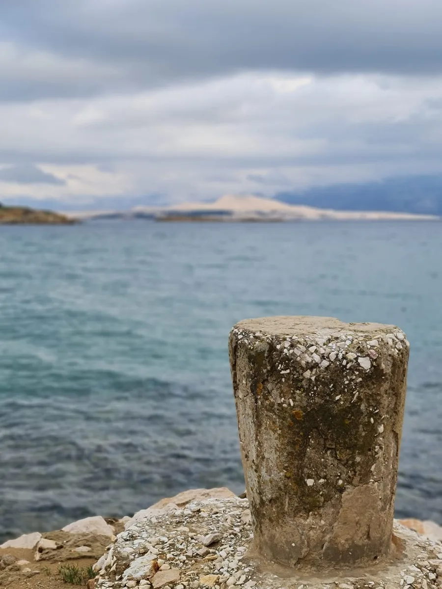 Stone pillar with turquoise sea in the background